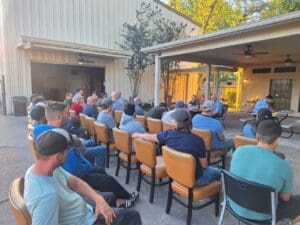 A group of people sitting in chairs outside.