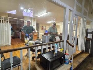 Two men in a room with a television and coffee maker.