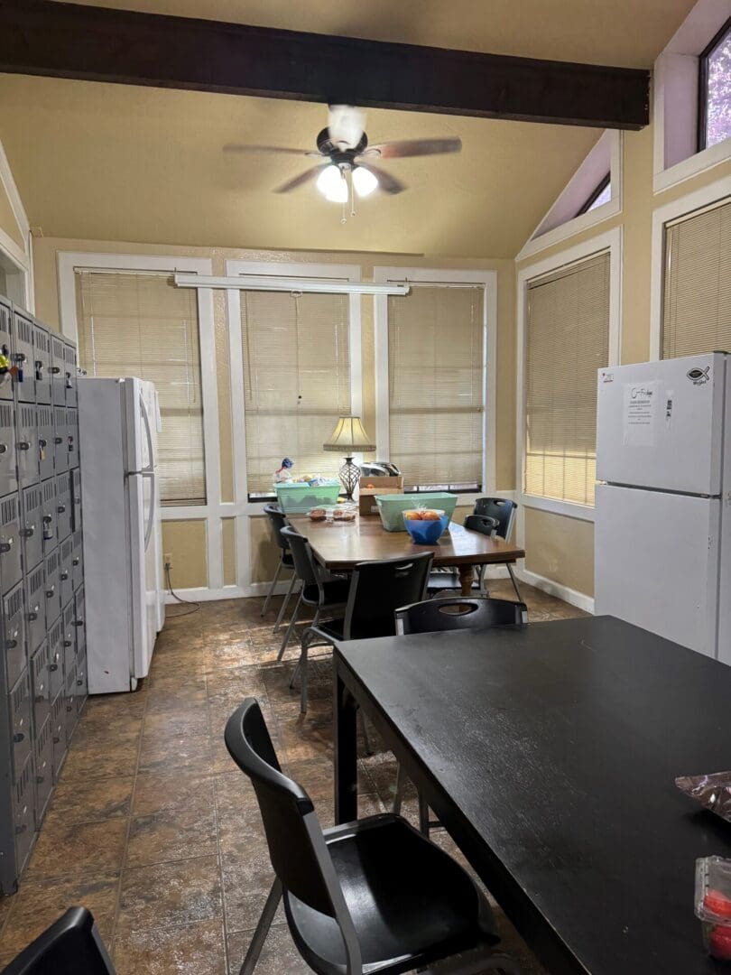 A kitchen with a table and chairs, refrigerator, microwave, and dining room.