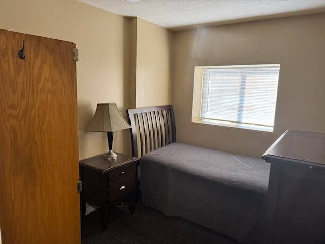 A bedroom with a bed, nightstand and window.