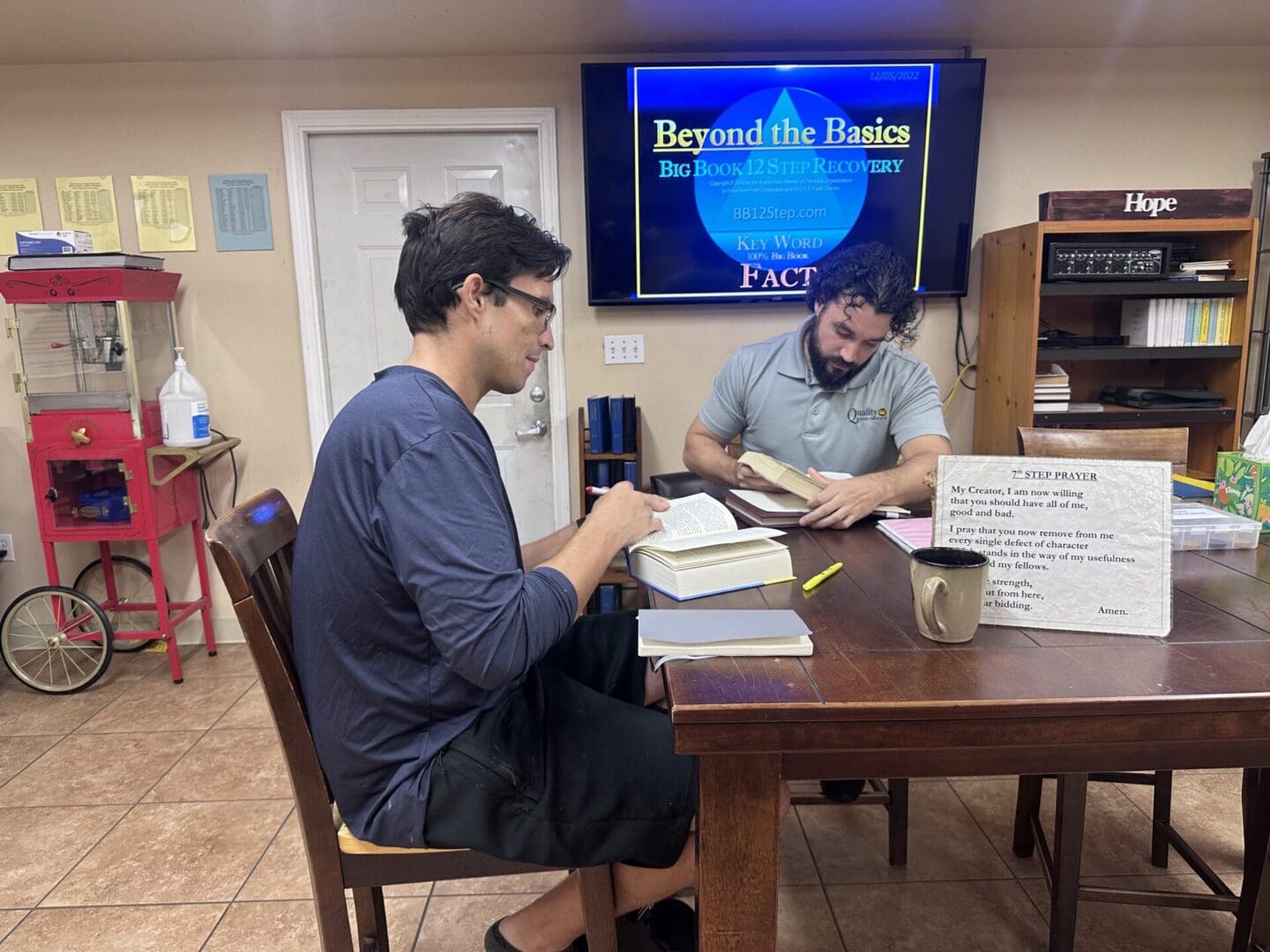 Two men sitting at a table with papers and books.